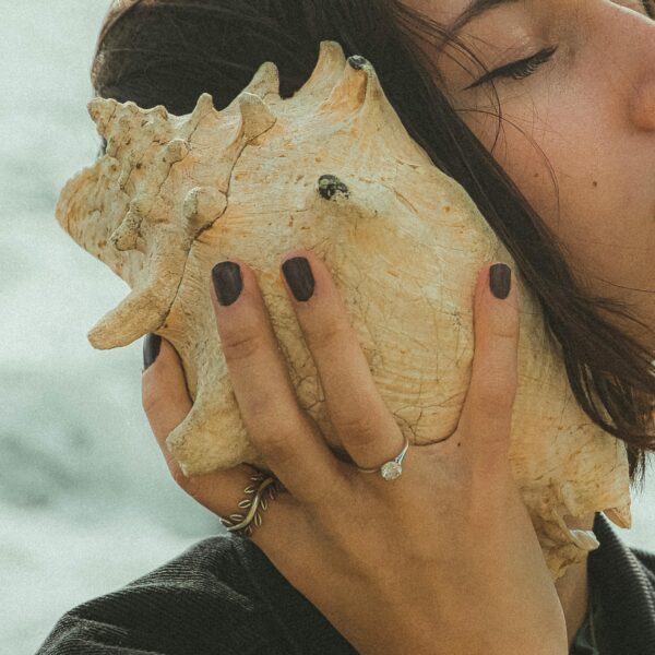 femme tenant un coquillage à son oreille, illustrant le fait d'écouter ce que son corps a à nous dire
